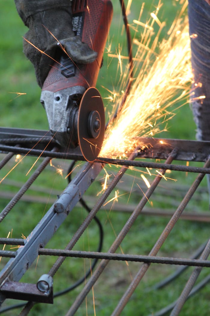 services-01 Detailed view of an angle grinder cutting metal, producing bright sparks in a workshop setting.